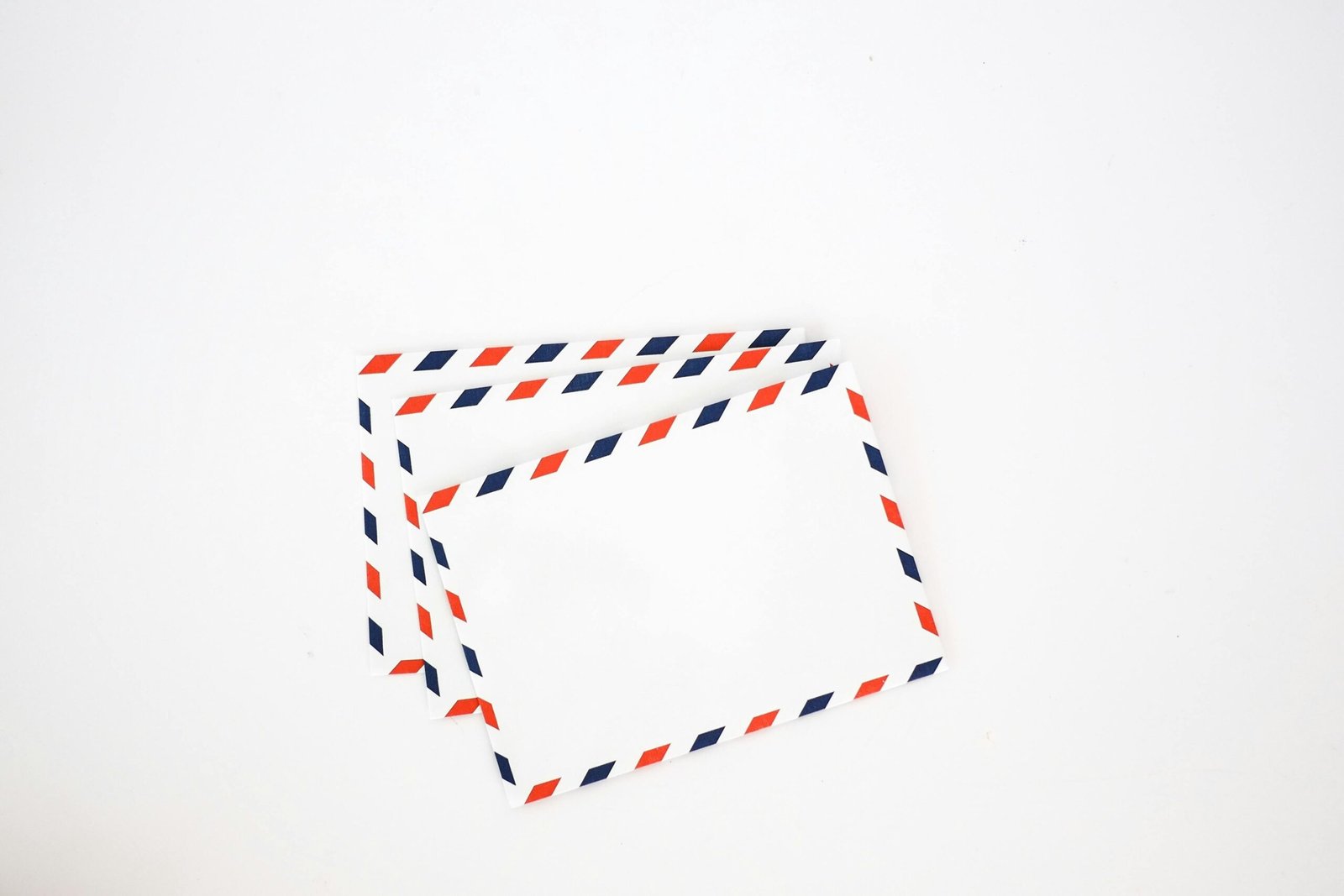 Top view set of white envelops with striped red and blue edges placed on plain white background